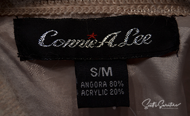 Label tag of Connie A. Lee woman's beige angora cardigan sweater showing size small-medium and fabric content.
