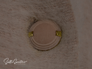 Close-up of beige angora sweater cardigan button by Connie A. Lee