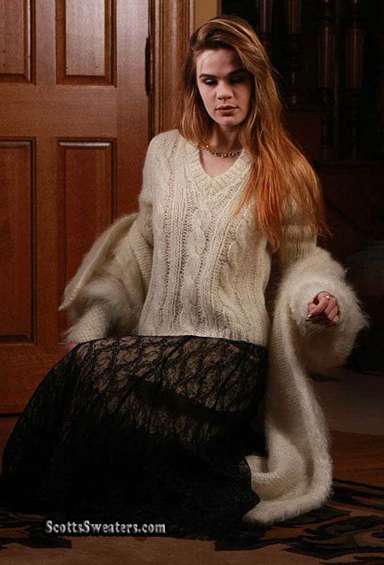 Woman wearing ivory full-length mohair sweater-coat and black lace skirt indoors