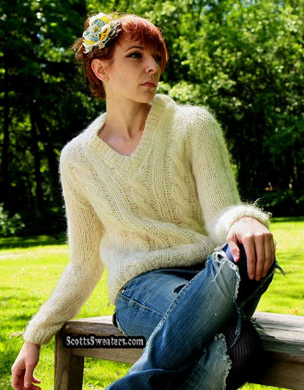 Woman's ivory cable-knit V-neck mohair sweater worn by a woman sitting outdoors