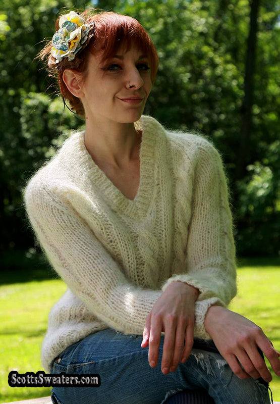 Woman wearing an ivory cable-knit V-neck mohair-wool sweater outdoors