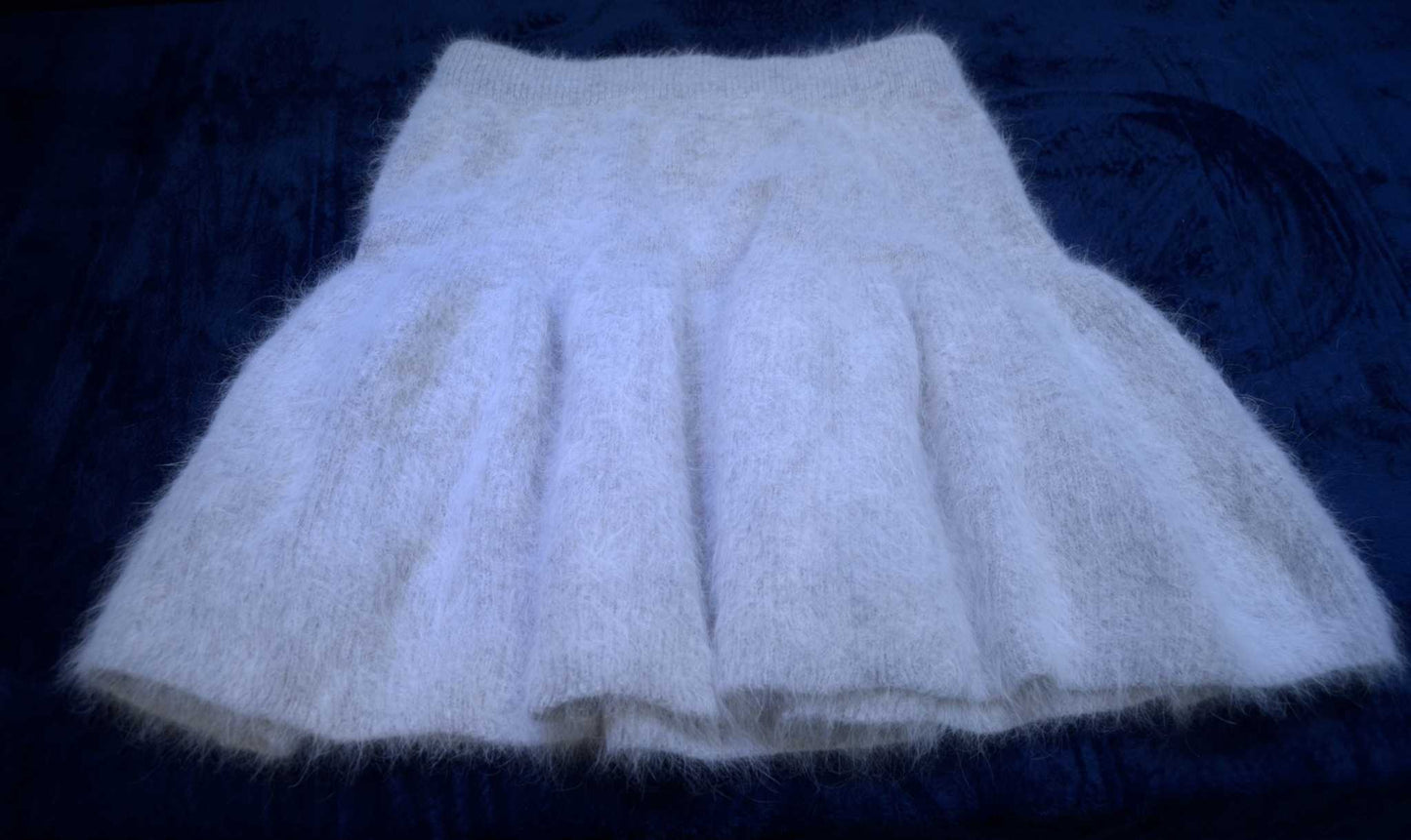 Soft white woman's short angora skirt with elastic waistband on dark background