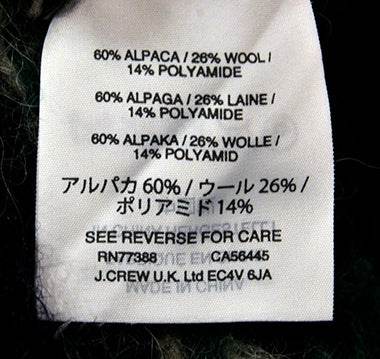 Men's navy-blue alpaca wool crewneck sweater fabric label showing material composition and care instructions