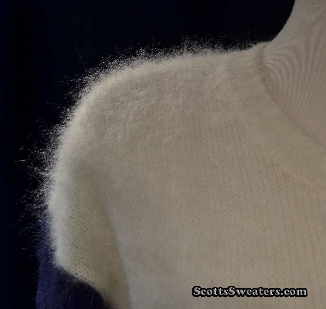 Close-up of a fuzzy white mohair color-block sweater with navy and red accents, round neck, small-medium size.
