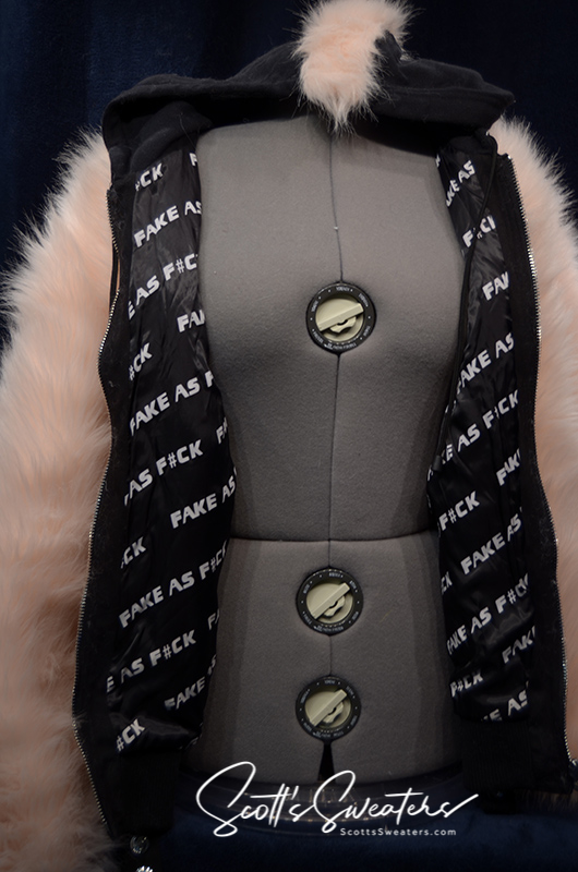 Punk style thick and fluffy faux-fur jacket with zipper front, hanging straps, metal D-rings, mohawk hood, and bold printed nylon lining.