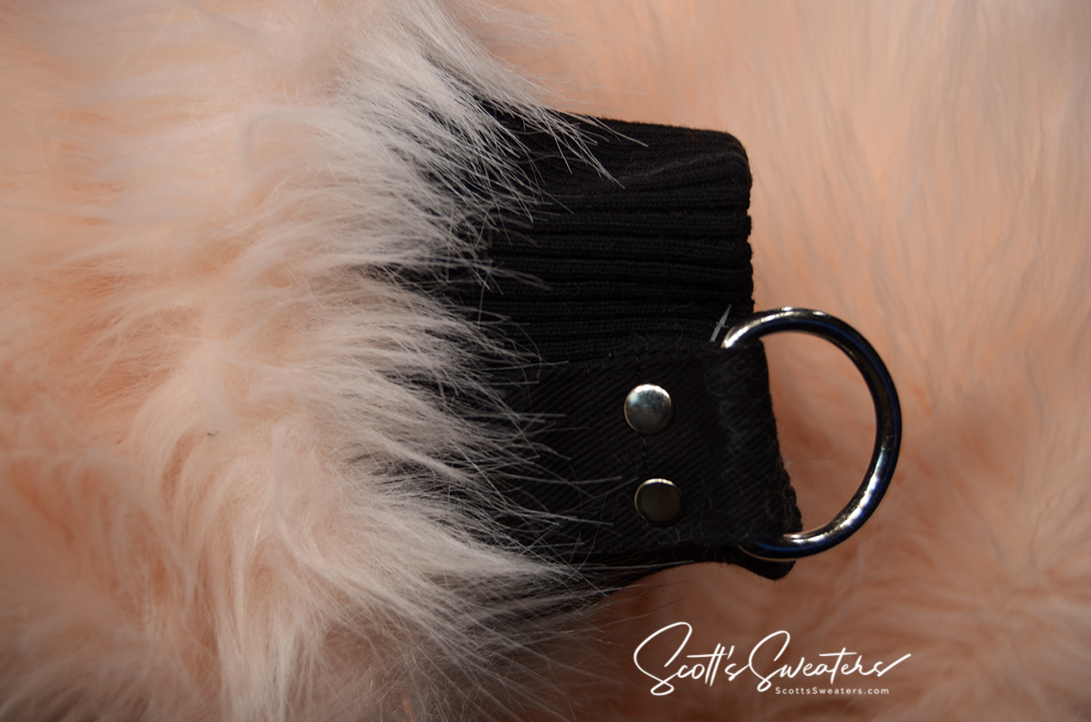 Close-up of punk style thick fluffy faux-fur jacket cuff with black strap and metal D-ring detail