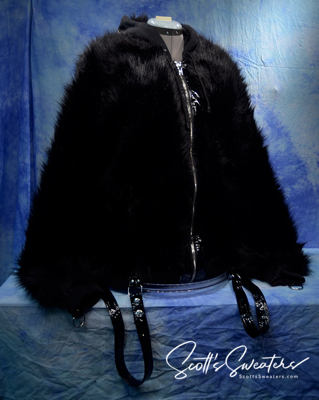 Punk style thick and fluffy black faux-fur jacket with zipper front, hanging straps, metal D-rings on cuffs, and mohawk hood design