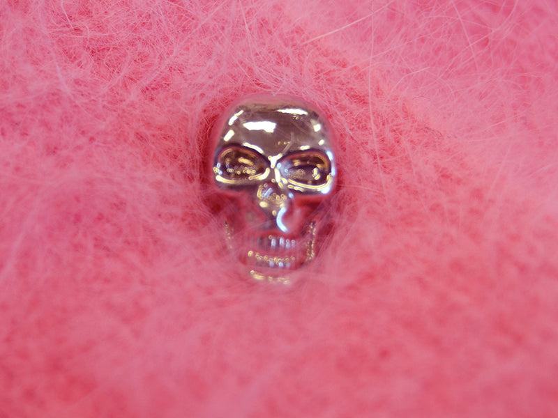 Close-up of chrome skull button on woman’s goth pink angora cardigan sweater