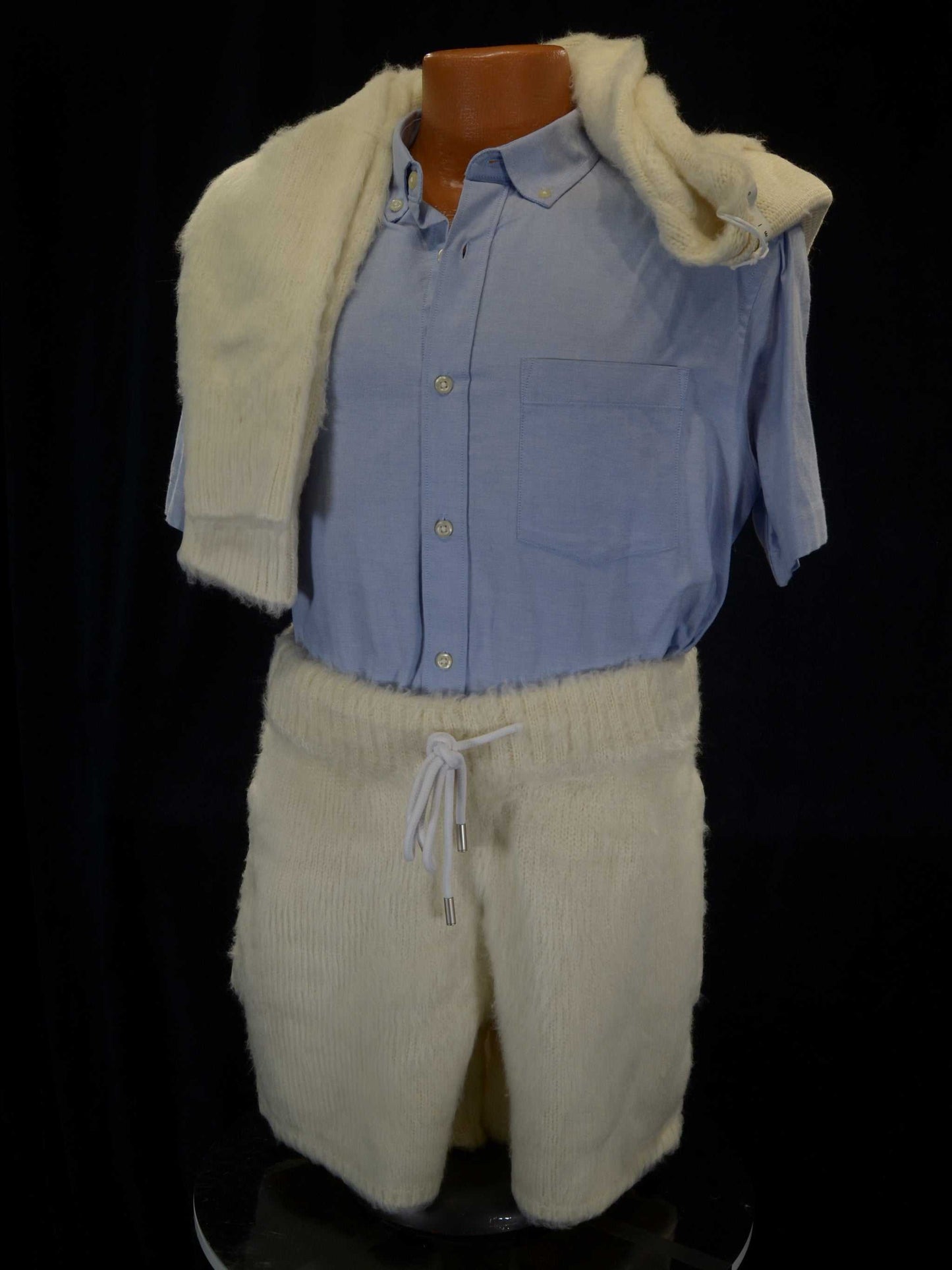 Men's fuzzy cardigan and matching shorts outfit in ivory with drawstring waistband and pockets, styled over a blue button-up shirt.