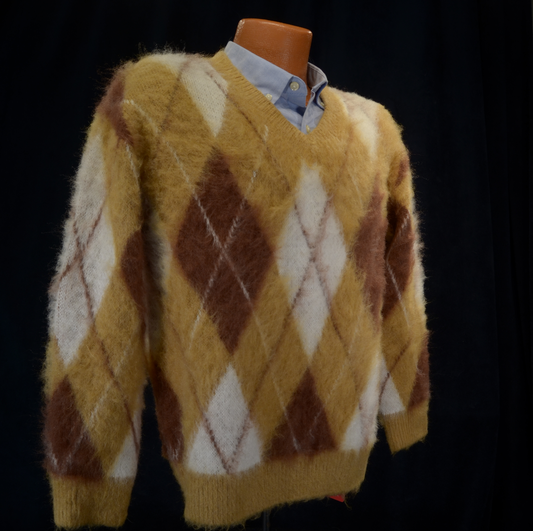 Fuzzy argyle V-neck pullover sweater in warm mustard, brown, and cream tones with a soft faux mohair texture.