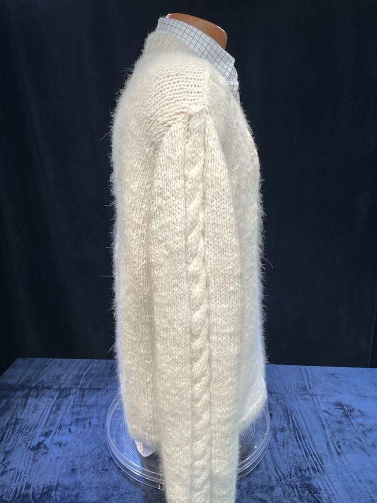 Men's home-spun angora-silk hand-knit white sweater with cable knit sleeves on mannequin against black background