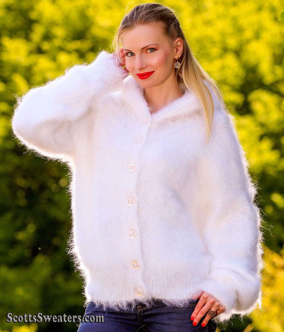 Woman wearing white hand-knit mohair sweater jacket with hood and buttons outdoors