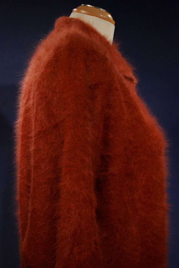 Rust-colored woman's angora polo-neck sweater on mannequin against dark background