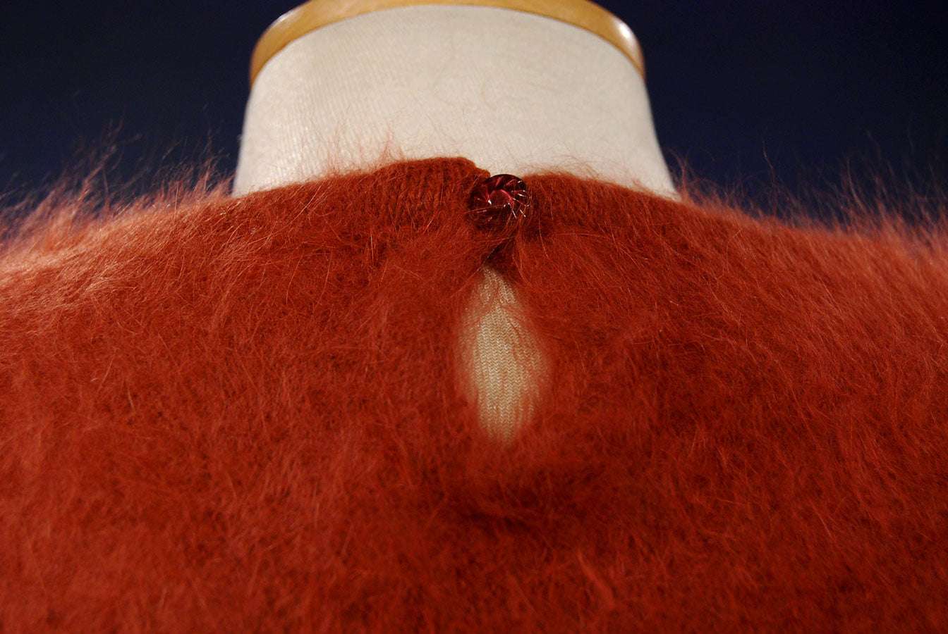 Brick-red woman's angora jewel-neck sweater with button closure on mannequin
