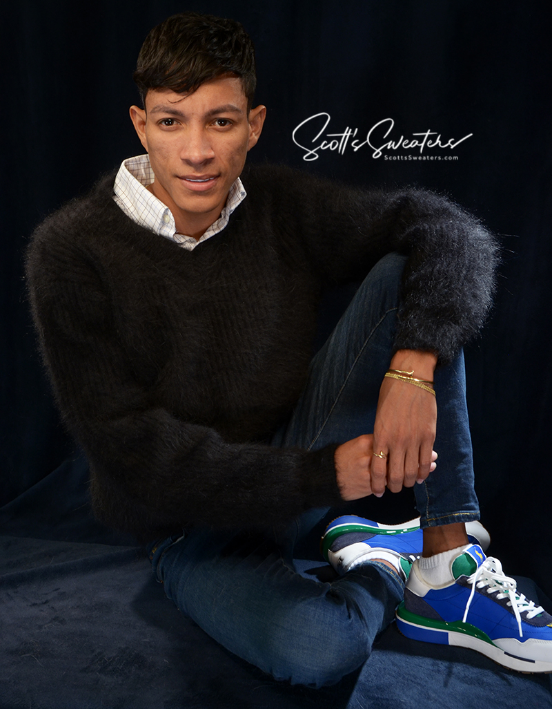 Men's soft luxurious black angora rib-knit V-neck sweater worn by male model sitting cross-legged