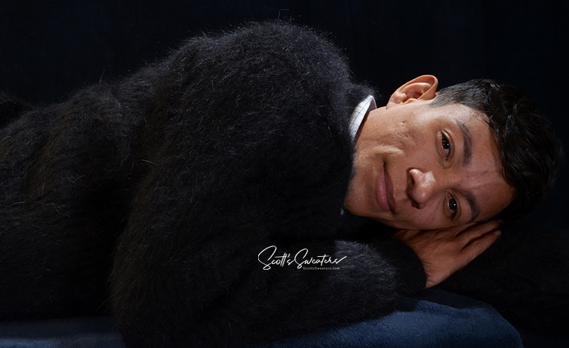 Men's soft luxurious black angora sweater with rib-knit texture and V-neck design worn by man lying down