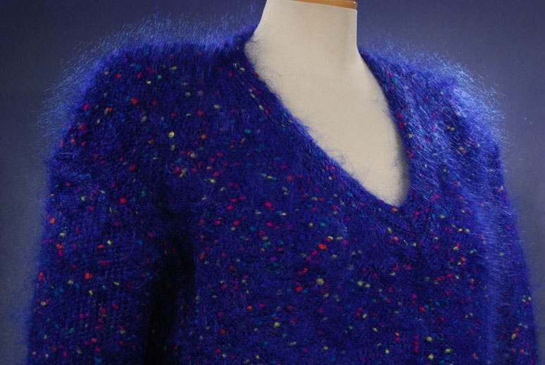 Woman's fuzzy blue speckled mohair V-neck sweater with red, green, yellow, and blue knit-in specks