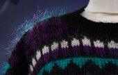 Close-up of woman's black multi-color striped mohair crewneck sweater with purple, white, and teal patterns