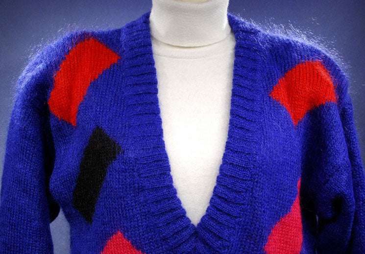 Woman's colorful deep V-neck sweater with red and black geometric design on blue knit by Nell Flowers