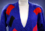 Woman's colorful deep V-neck sweater with red and black geometric design on blue knit by Nell Flowers
