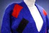 Woman's colorful deep V-neck sweater with red and black geometric design on blue background