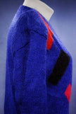 Woman's colorful deep V-neck jewel-tone sweater with red, black, and green geometric design by Nell Flowers