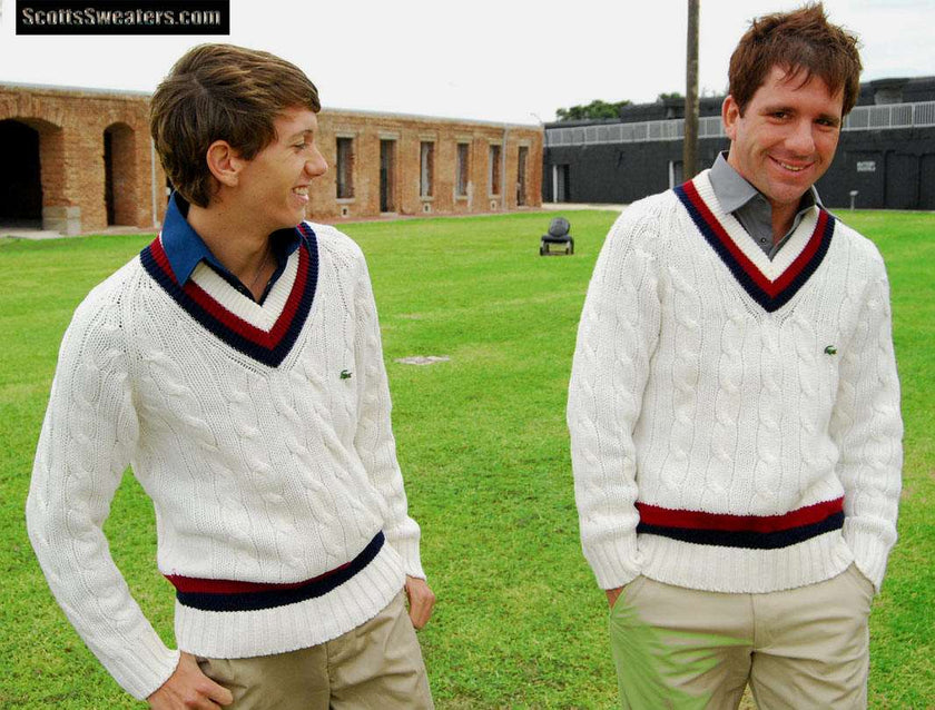 Two men wearing Men's Classic Retro Izod tennis sweaters with white cable knit and burgundy/navy stripe neckbands outdoors on grass