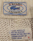 Close-up of Izod Lacoste label and fabric texture on men's classic retro cable-knit tennis sweater made of 100% acrylic