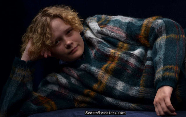 Vintage mohair sweater with shaggy plaid pattern and V-neck worn by model reclining against dark background