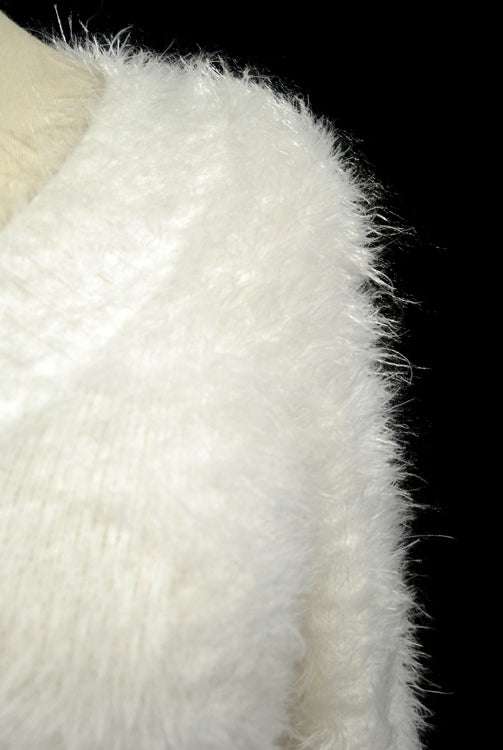 Close-up of woman's white ultra-soft fuzzy V-neck sweater fabric against black background