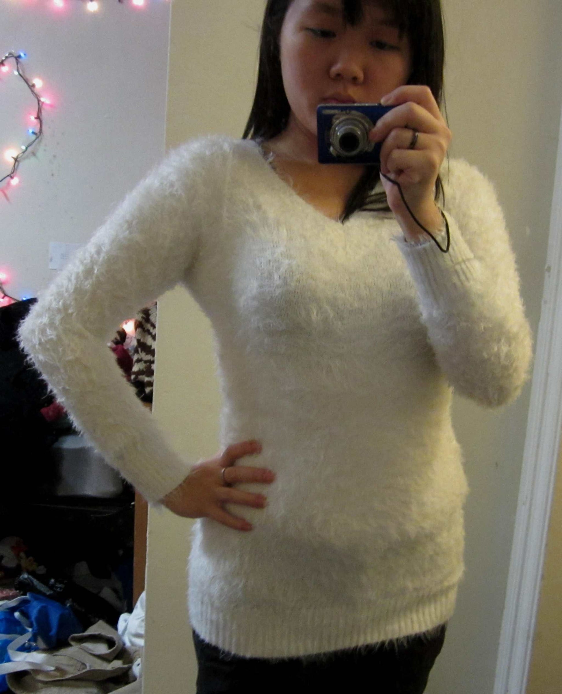 Woman wearing white ultra-soft fuzzy V-neck sweater with long sleeves and cling fit