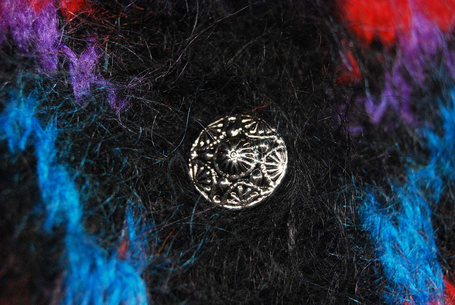 Close-up of metal button on colorful woman’s mohair cardigan sweater by Icelandic design