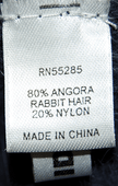 Close-up of a clothing label showing fabric composition of 80% angora rabbit hair and 20% nylon for a woman's angora shrug cardigan by Express.