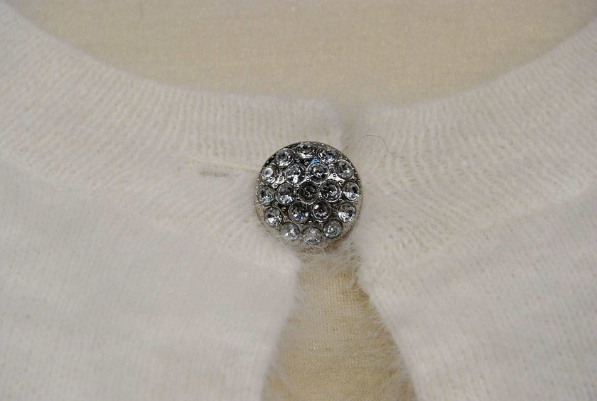 Close-up of jeweled rhinestone button on woman's white angora shrug cardigan sweater by Express