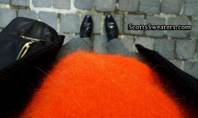 Woman's soft fuzzy orange angora jewel-neck sweater by H&M, size medium, styled with black coat and gray pants on cobblestone background