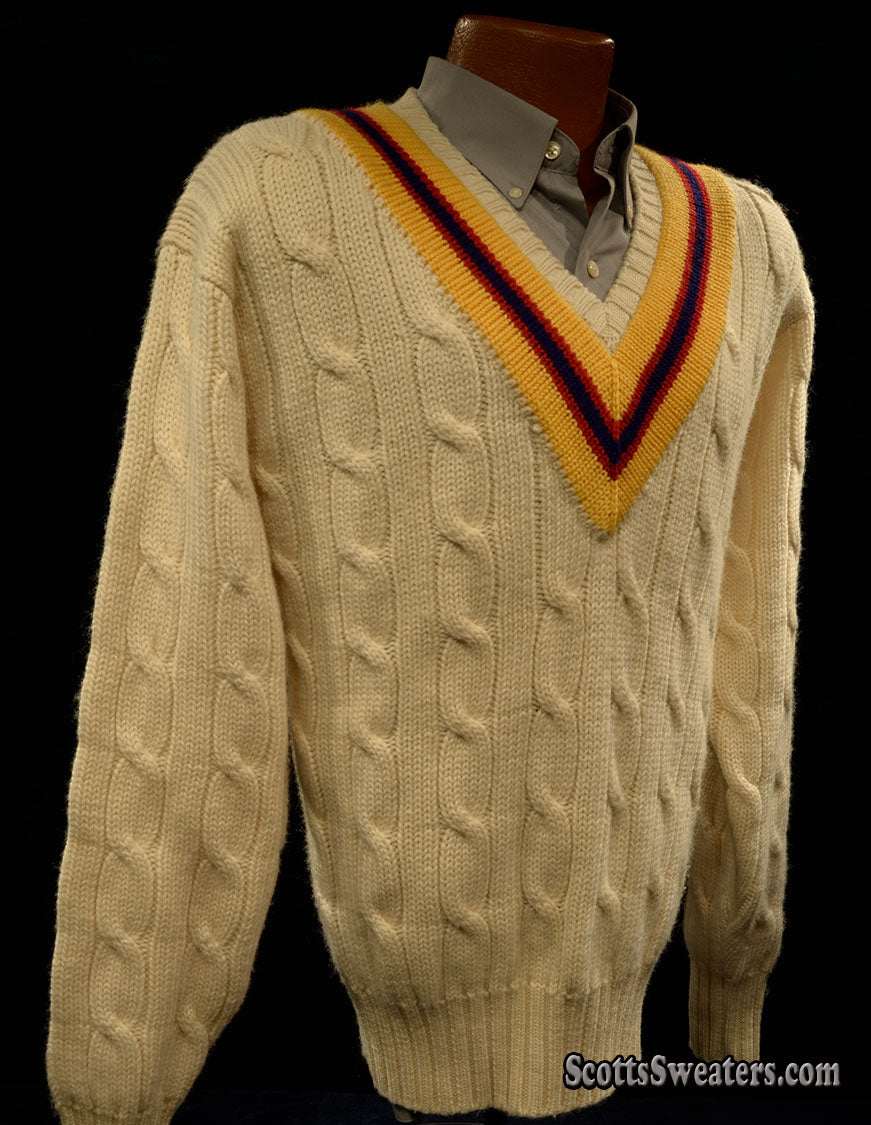 Ivory cable-knit wool tennis sweater with yellow, blue, and red striped V-neck collar