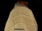 Ivory cable-knit wool tennis sweater with yellow, blue, and red striped neckline on mannequin