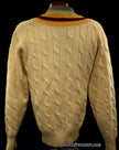 Ivory cable-knit wool tennis sweater with yellow, blue, and red striped neckline, classic thick design.
