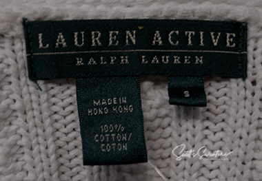 Close-up of label on woman's white cable-knit cardigan by Ralph Lauren Active showing fabric details and size small