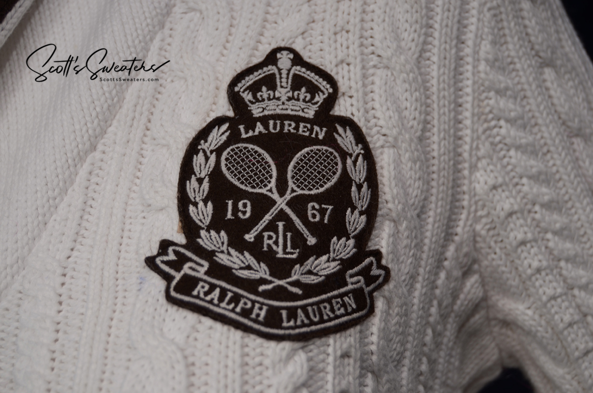 Close-up of Woman's white cable-knit cardigan showing Ralph Lauren tennis crest patch