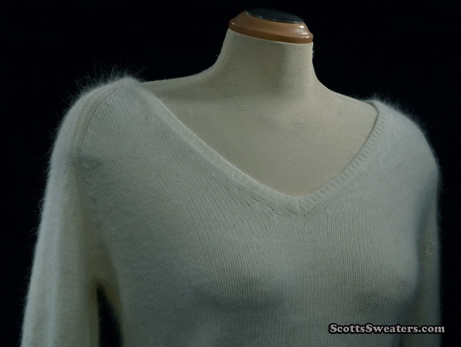Woman's white angora V-neck sweater with split cuffs by H&M on mannequin