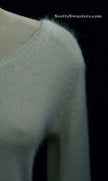 Close-up of woman's white angora V-neck sweater with soft texture and split cuffs detail