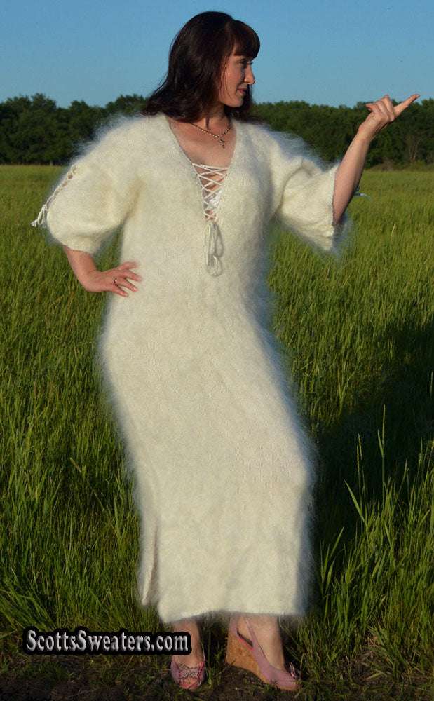 Woman wearing ivory fuzzy mohair full-length sweaterdress with open-lace neckline and half sleeves standing in a grassy field