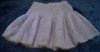 Soft beige woman's short angora skirt with elastic waistband laid flat on dark fabric background