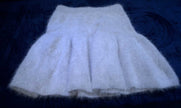 Soft white woman's short angora skirt with elastic waistband on dark background