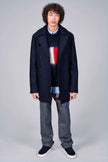 Men's black crewneck Tommy Hilfiger mohair sweater with large flag logo on chest, styled with navy coat and gray pants