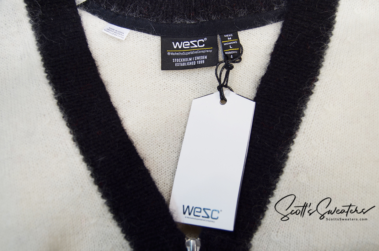 Close-up of WeSC skateboarder street wear mohair cardigan sweater with black trim and white tag, size medium.