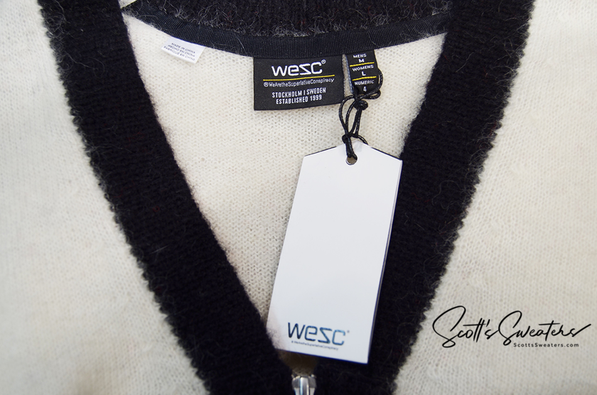 Close-up of WeSC skateboarder street wear mohair cardigan sweater with black trim and white tag, size medium.