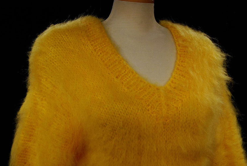 Woman's fuzzy yellow hand-knit mohair sweater with double V-neck design on mannequin