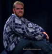 Men's argyle angora cardigan sweater in three-tone pattern worn by smiling man sitting against black background